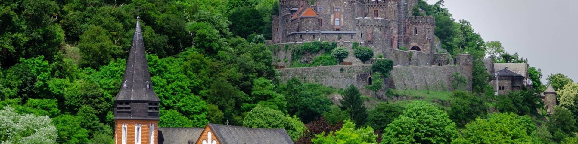 A church with a tall steeple and a castle on a hill.