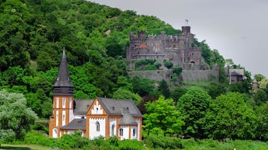 A church with a tall steeple and a castle on a hill.