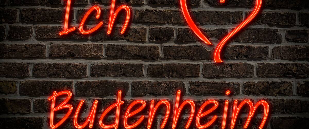 A neon sign on a brick wall with the text "Ich Buchenheim" and a heart symbol.