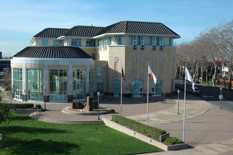 A modern building with a glass facade and a flagpole with flags.