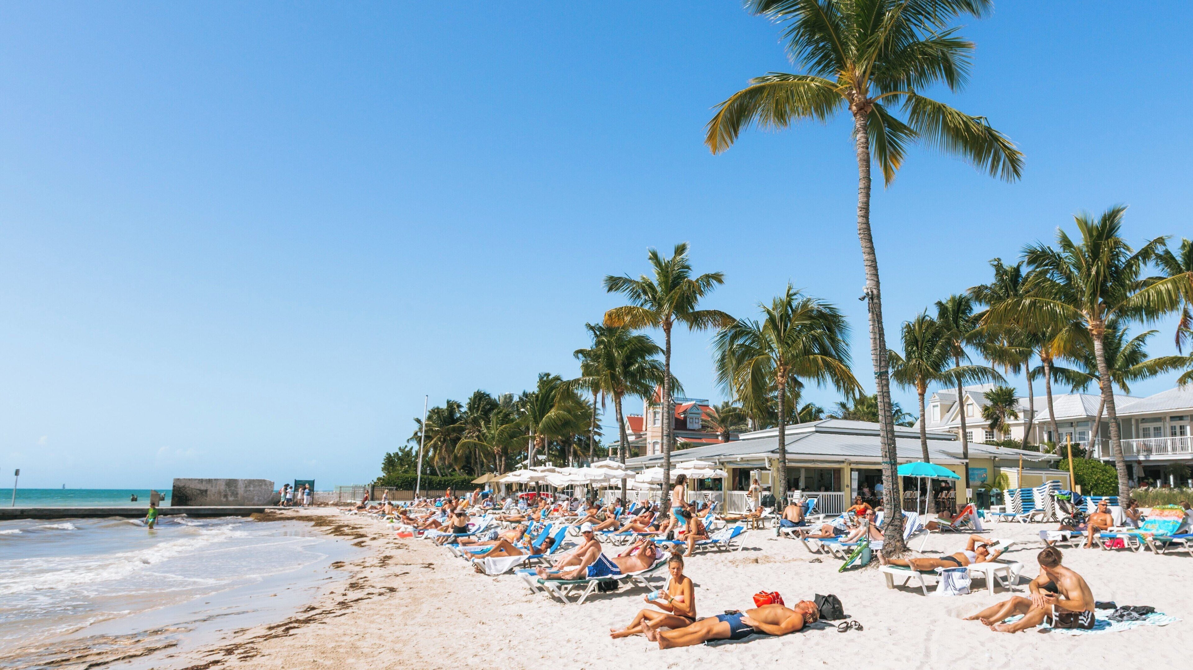 Vibrant afternoon at South Beach in Uptown Upper Duval, Key West, Florida with sunbathers enjoying the warm sun and ocean view
