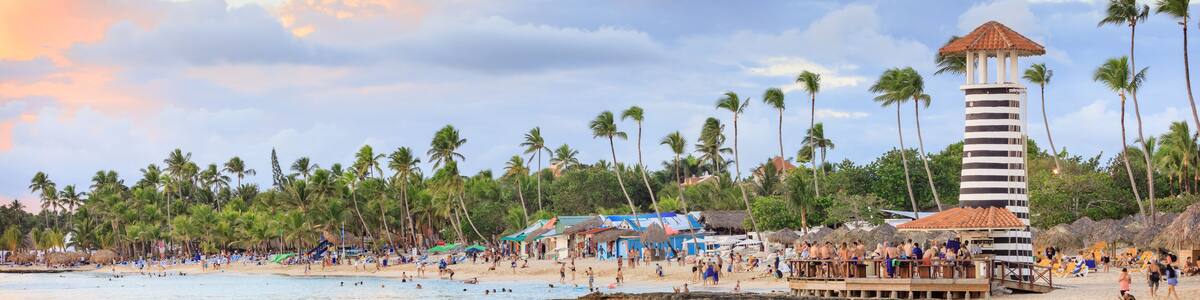 A beach with palm trees, a lifeguard tower, and beachgoers.