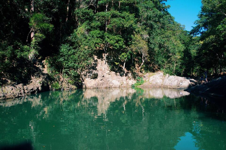 Une rivière paisible, bordée d’une forêt dense et d’un paysage rocheux.