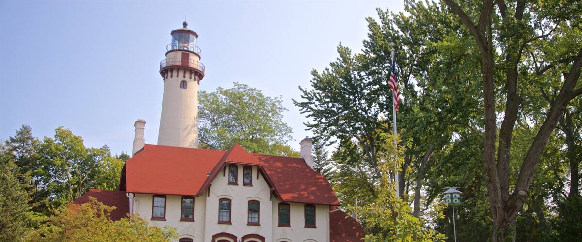 A historic building with a lighthouse, surrounded by lush greenery and trees.