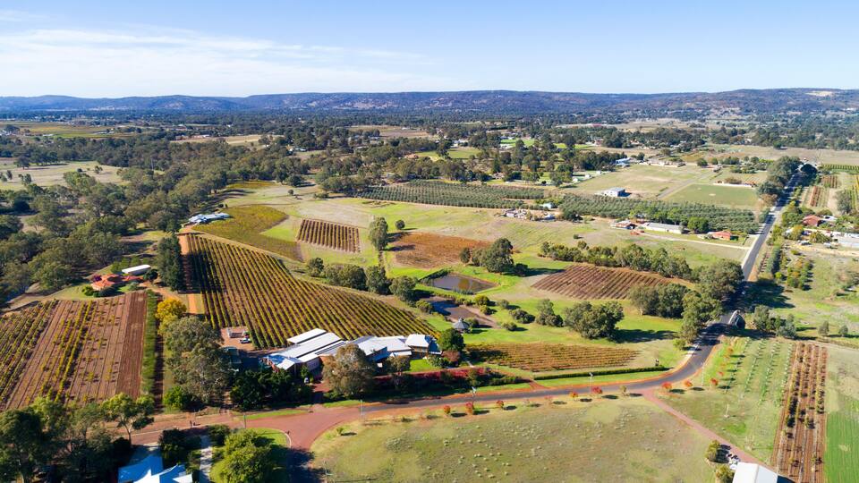An aerial view of a rural landscape with fields, a road, and scattered buildings.