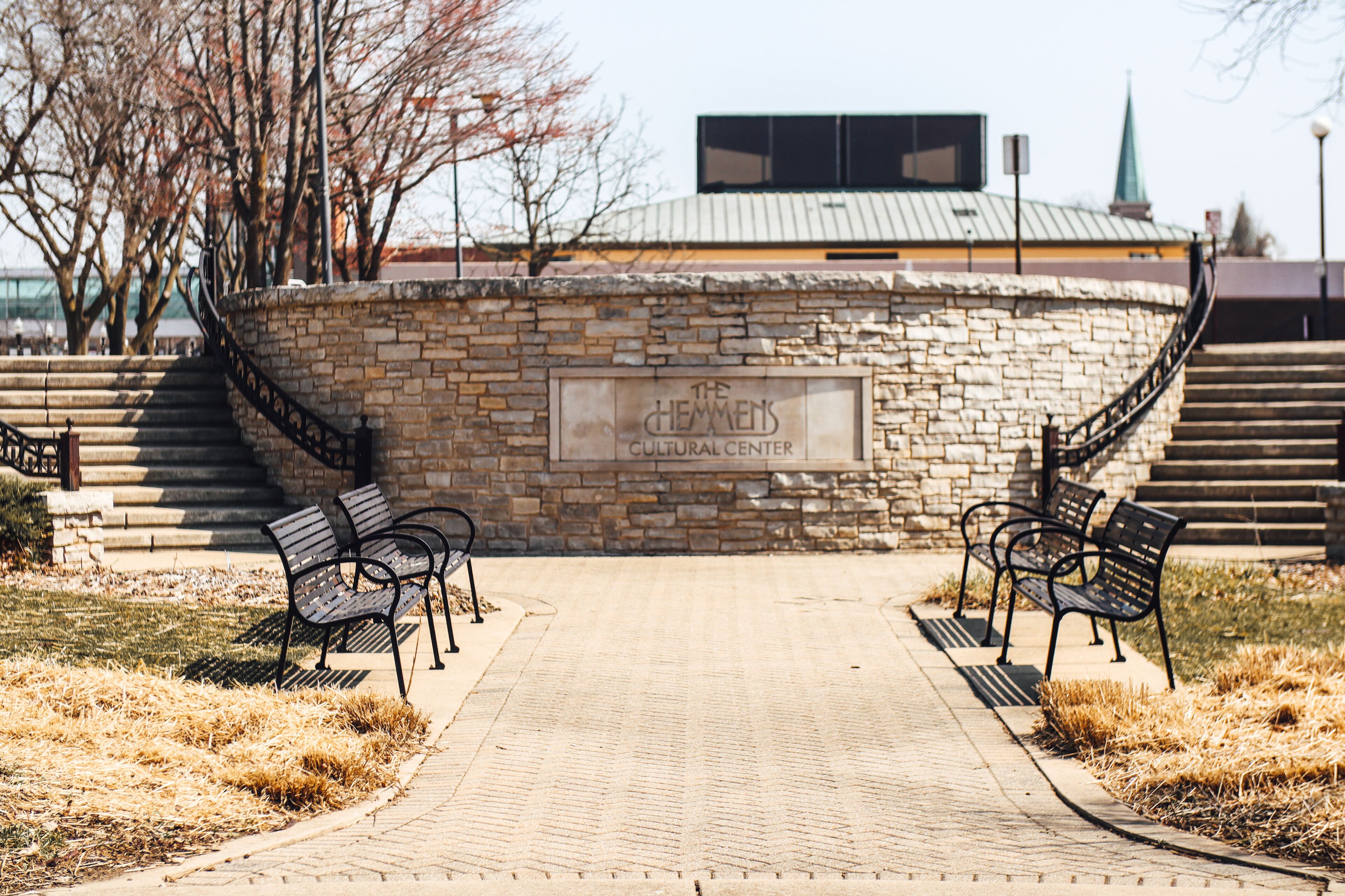 Outdoor park of The Hemmens Cultural Center with metal benches and sidewalk stairways