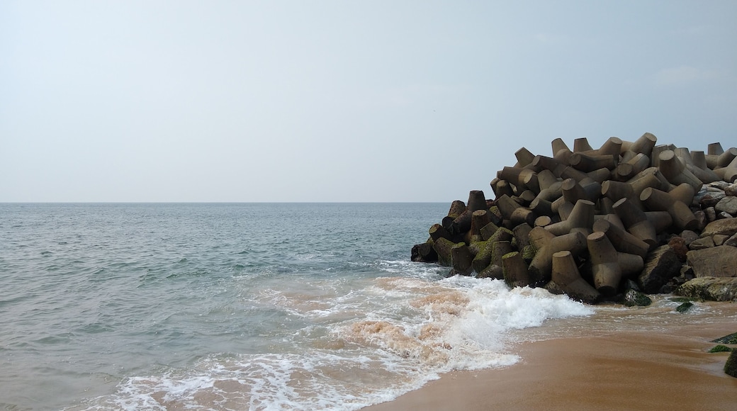 Ein Strand mit brechenden Wellen und einer Ansammlung zylindrischer Betonstrukturen.