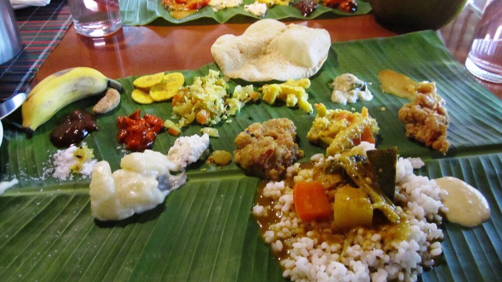A variety of dishes served on banana leaves, including rice, vegetables, and possibly meat.