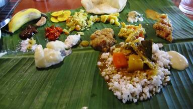 A variety of dishes served on banana leaves, including rice, vegetables, and possibly meat.