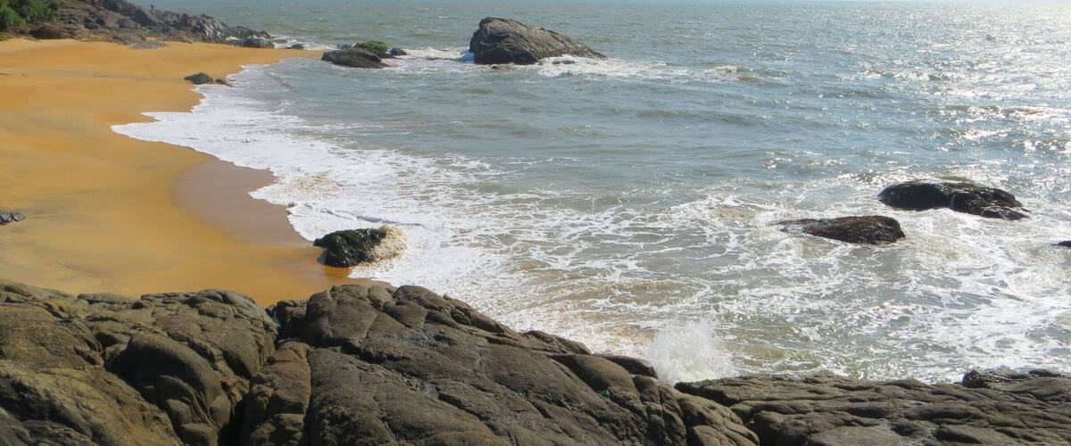 A rocky coastline with a sandy beach and waves crashing against the rocks.