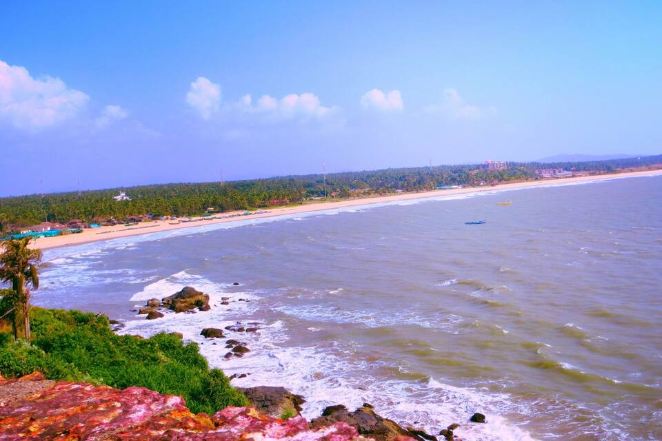 Una playa con olas, una costa lejana y un área boscosa.