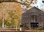 A rustic wooden barn surrounded by autumn trees.
