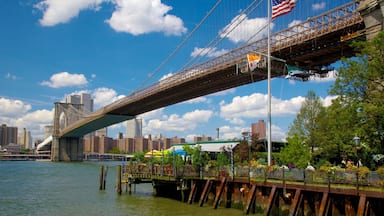 A bridge with an American flag, a city skyline, and a waterfront park.