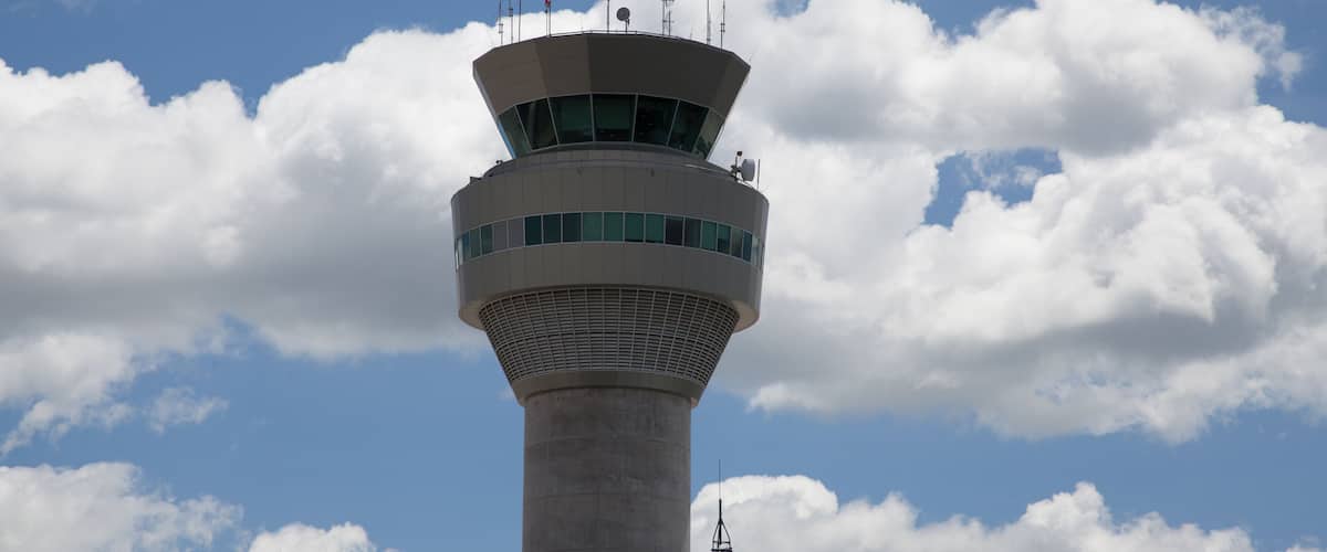A control tower with a clear sky and clouds.