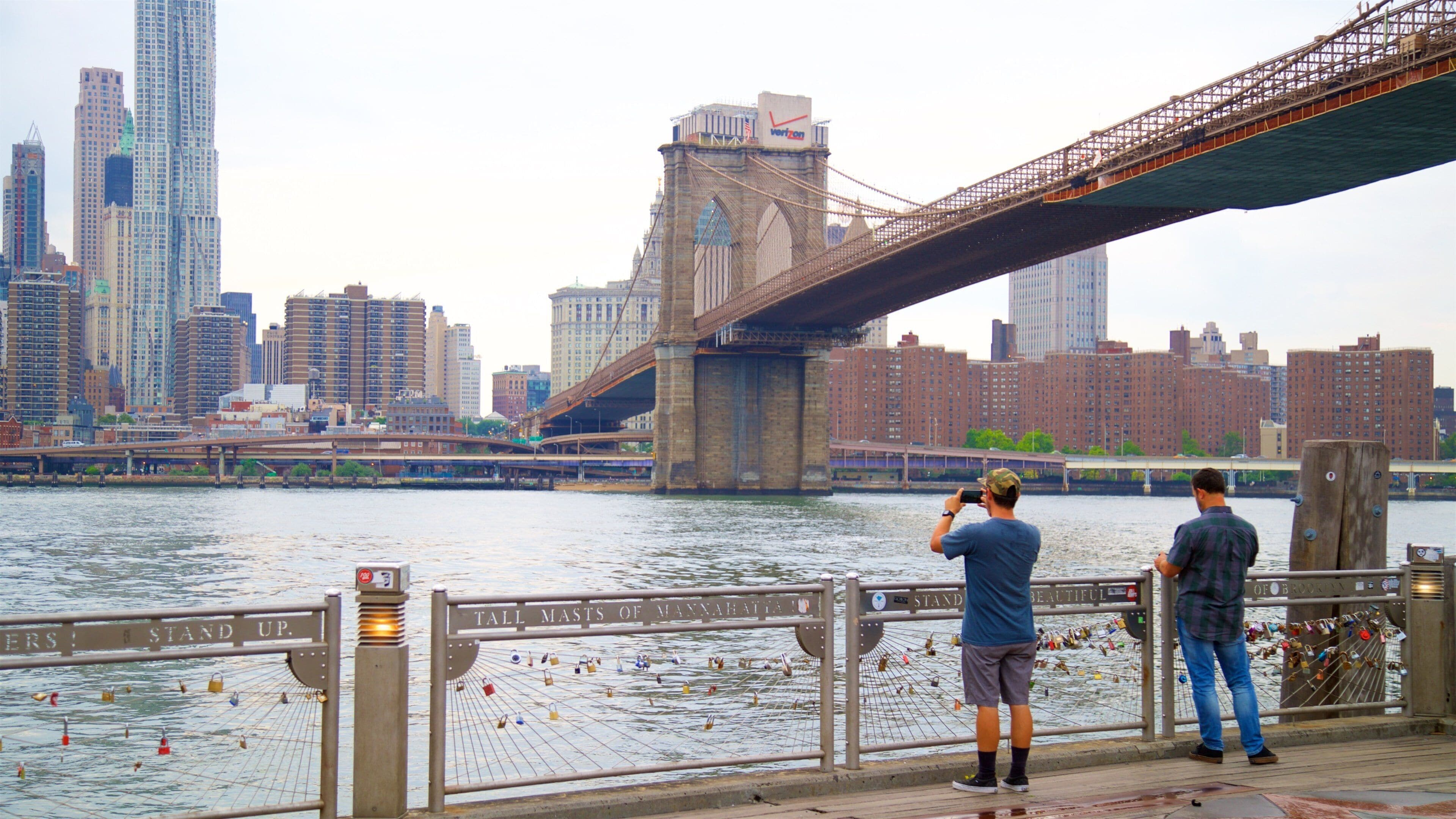 Eine Brücke über einem Fluss, im Hintergrund die Skyline einer Stadt.