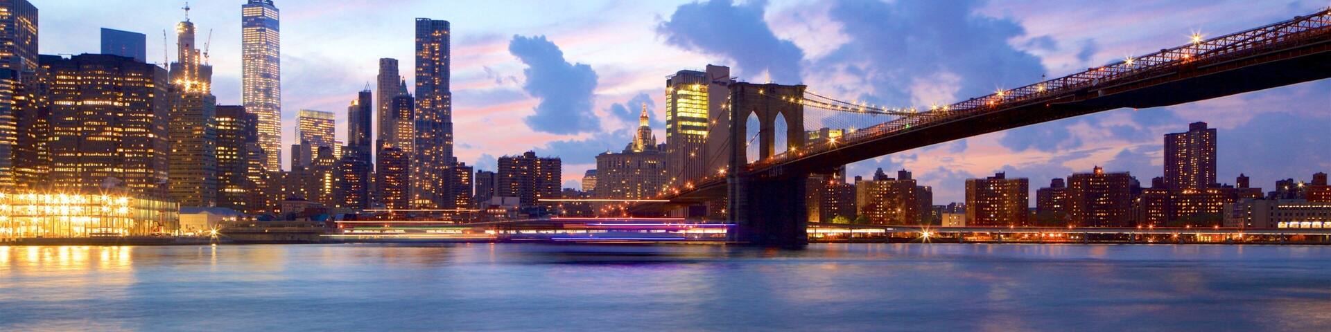 Un horizonte urbano con edificios iluminados y un puente sobre el agua.
