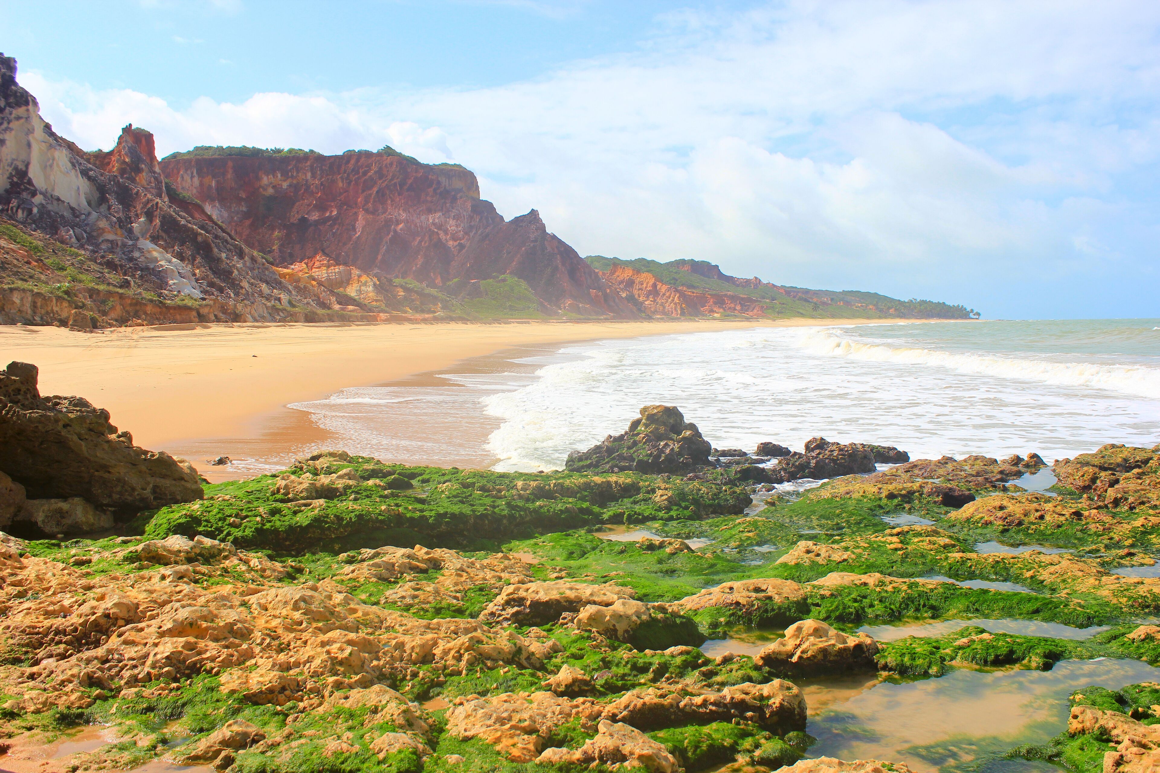 Rocks with moss and water on the foreground, Coqueirinho Beach on the backgroun