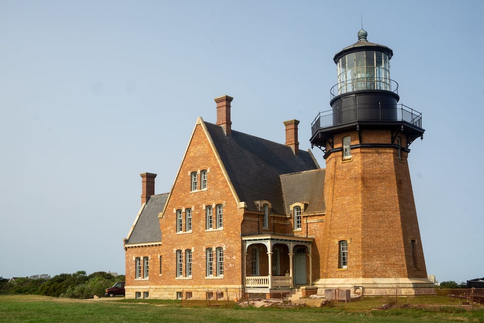 A brick lighthouse with a tower and a house.