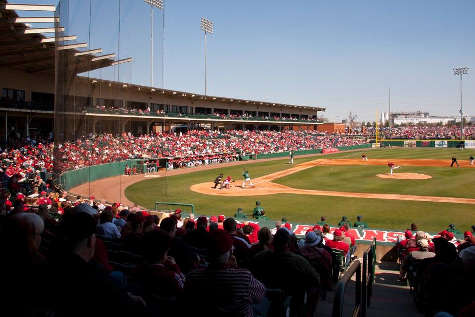 A baseball stadium filled with spectators, a baseball diamond, and a large scoreboard.