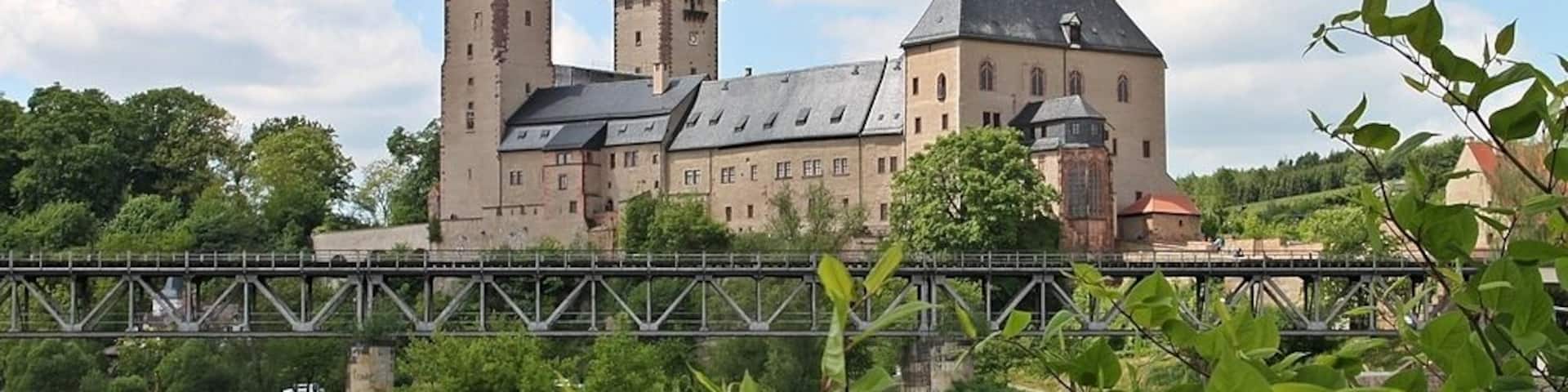 A historic castle with two towers and a bridge over a river.