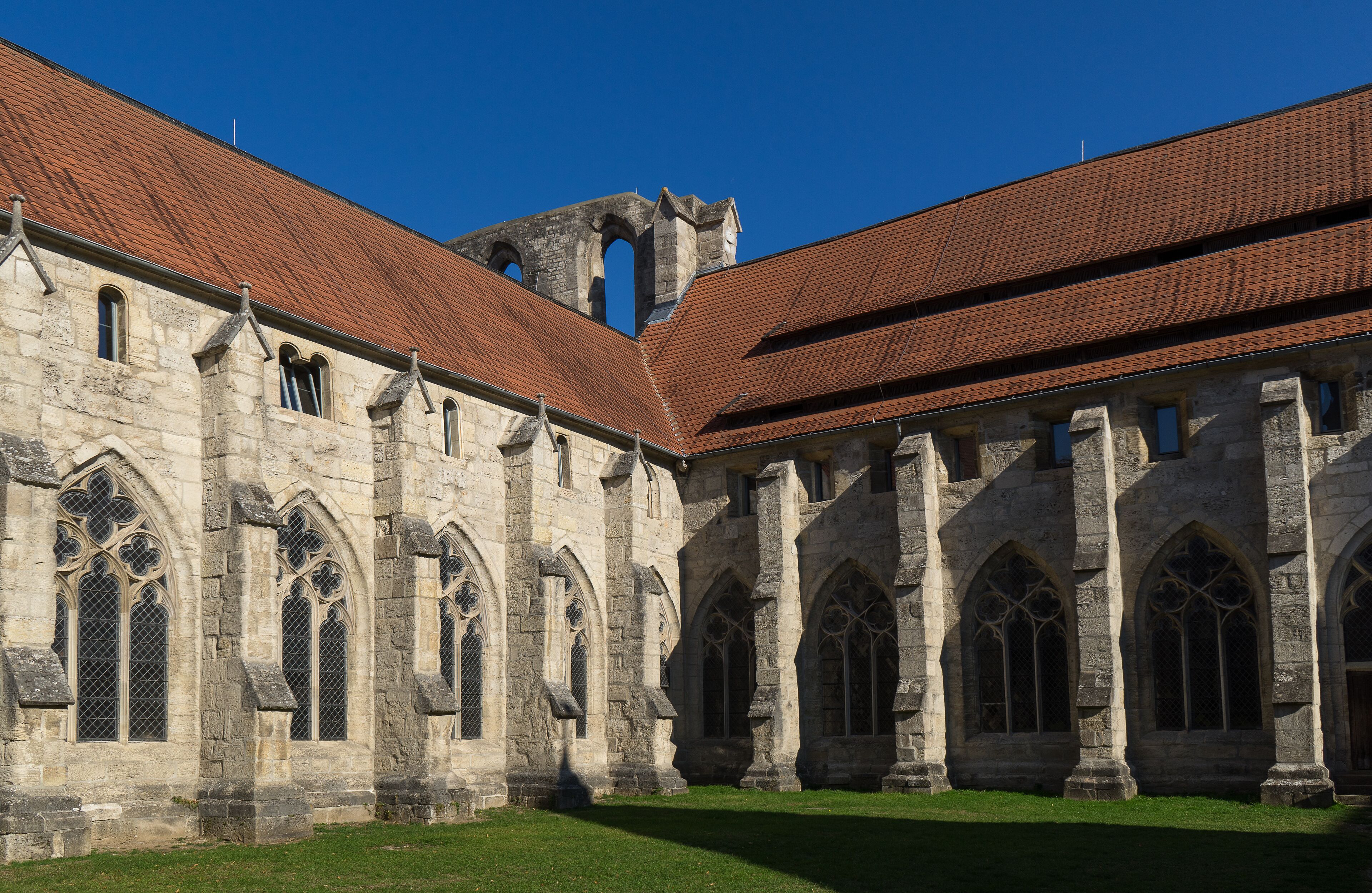 A historic stone building with arched windows and a red-tiled roof.