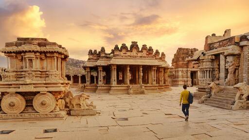 Ancient stone chariot with archaeological ruins in the courtyard of Vittala Temple at Hampi, Karnataka India at sunset