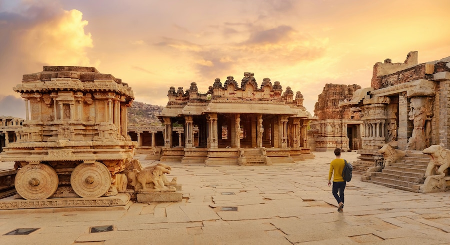 Ancient stone chariot with archaeological ruins in the courtyard of Vittala Temple at Hampi, Karnataka India at sunset