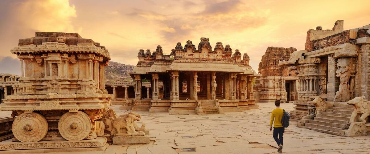 Ancient stone architecture with intricate carvings and a person walking in the foreground.