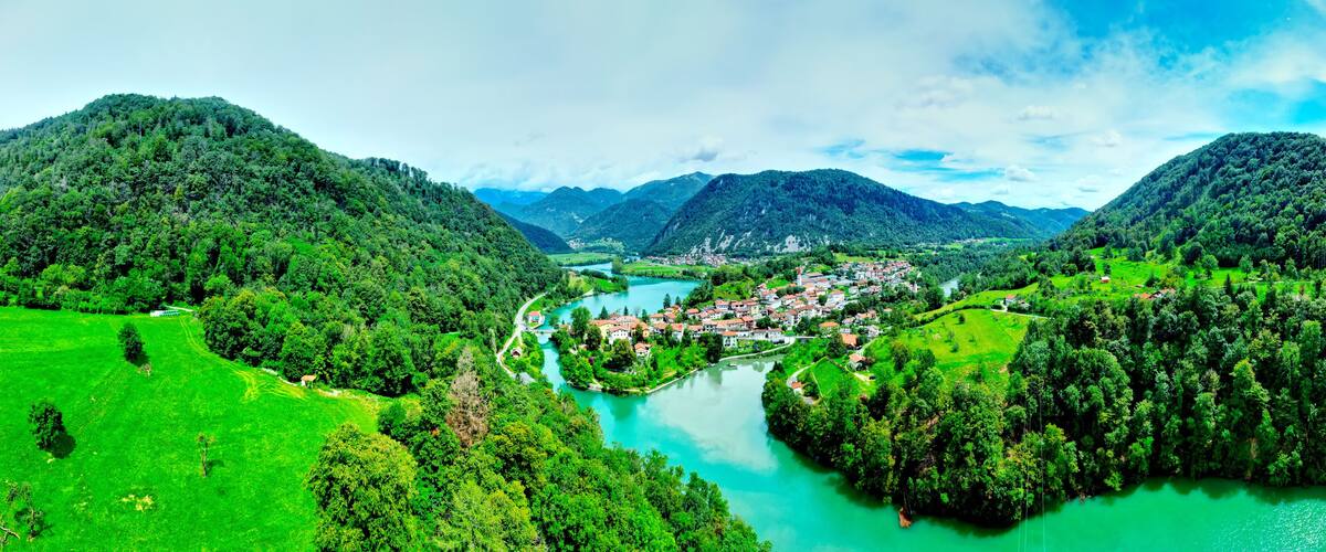 A river winding through a valley with a town on its banks, surrounded by lush green hills.