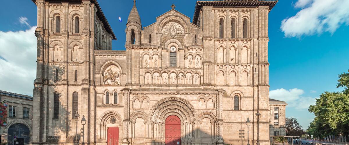 A historic cathedral with intricate stone carvings, a prominent red door, and a clock tower.