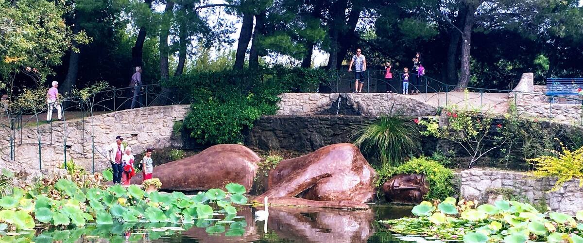 A pond with large rocks, lily pads, and a stone bridge.