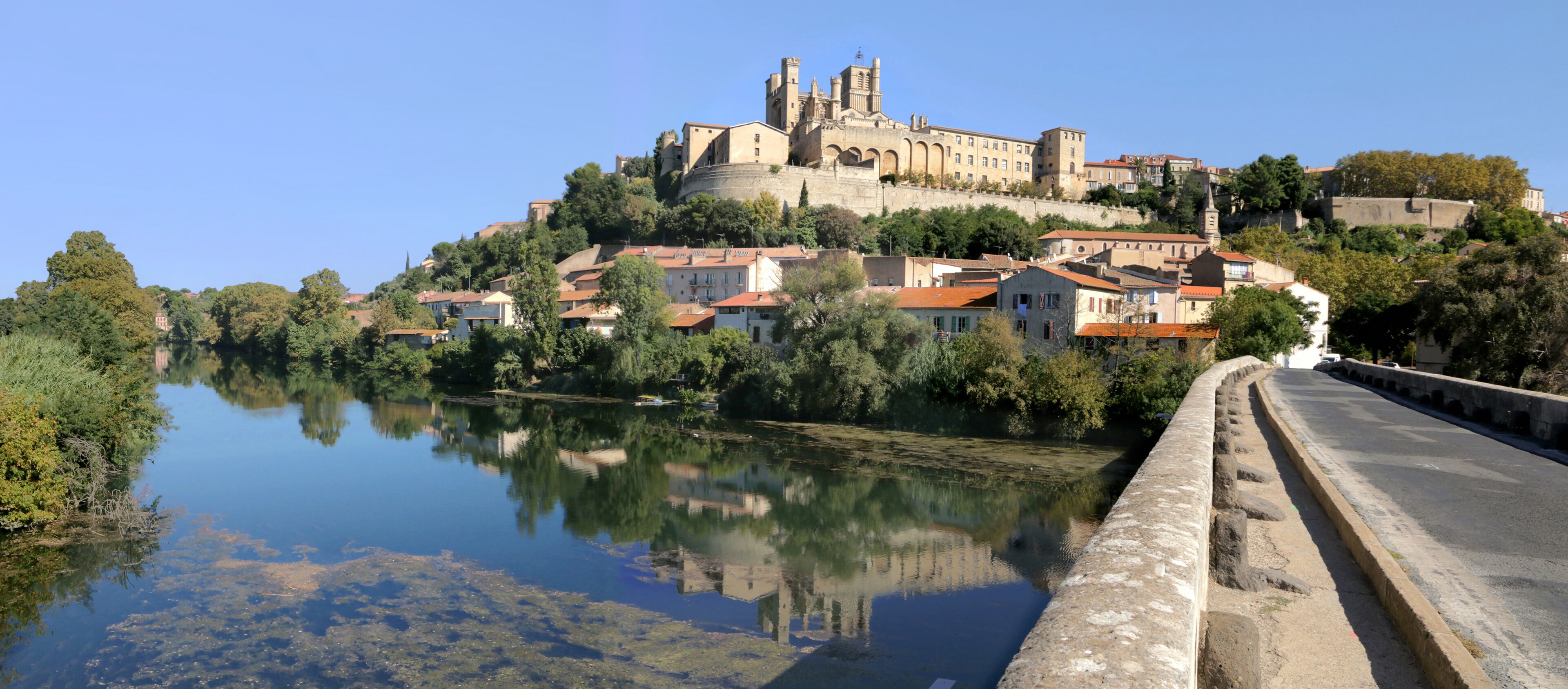 A historic castle on a hill with a river in the foreground.