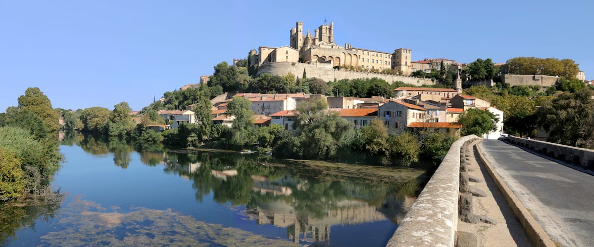 A historic castle on a hill with a river in the foreground.