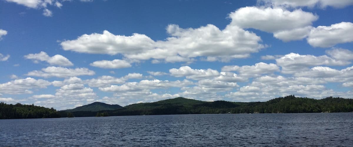 A lake with scattered clouds and a forested shoreline.