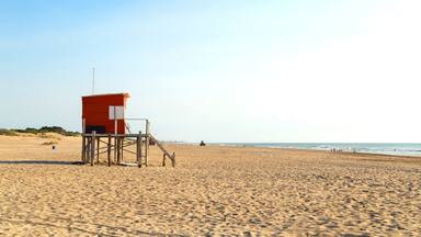 A sandy beach with a lifeguard tower and a distant shoreline.