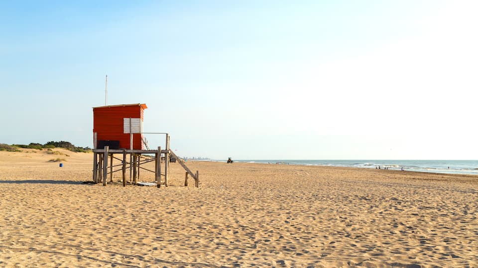 A sandy beach with a lifeguard tower and a distant shoreline.
