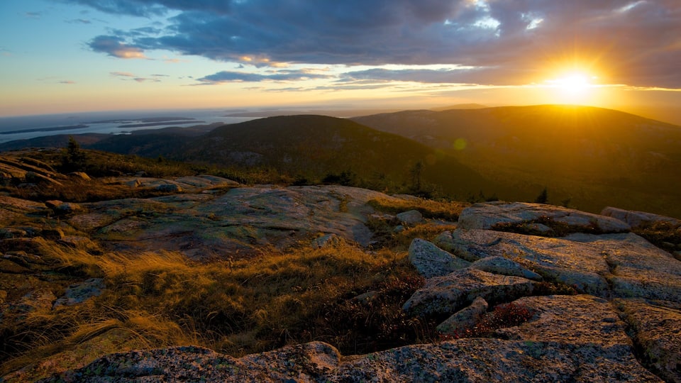 A mountainous landscape with rocky terrain and a sunset in the background.