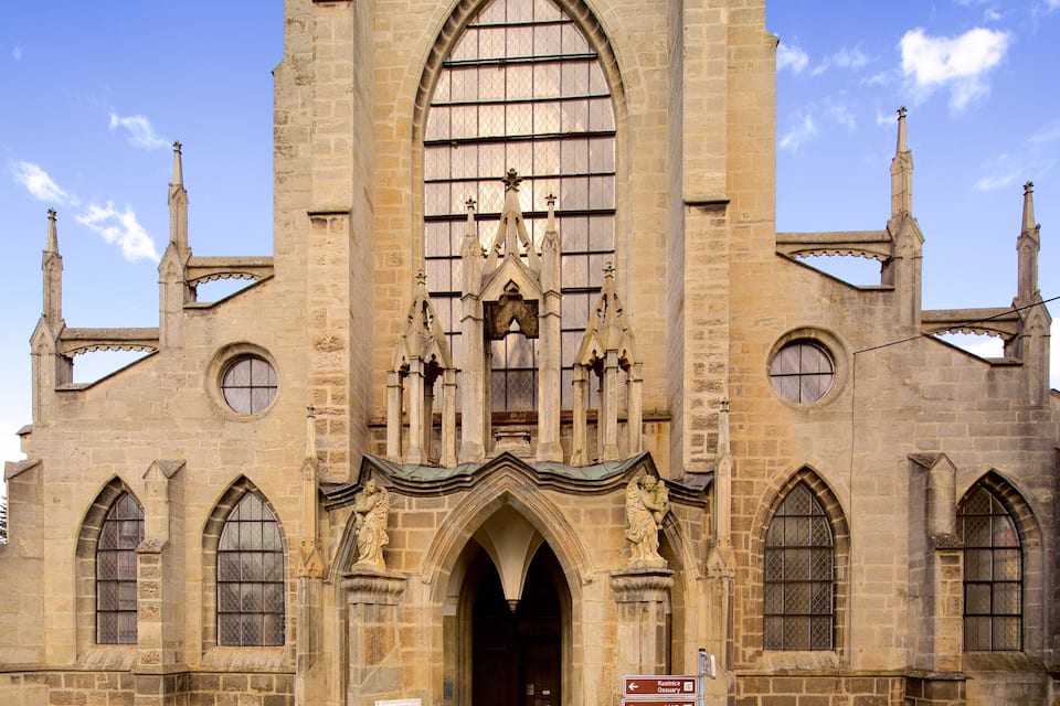 Una iglesia histórica de arquitectura gótica, con arcos apuntados, un gran rosetón central y estatuas en la entrada.