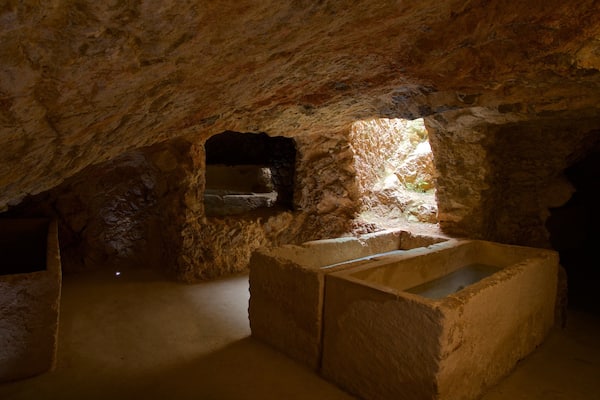 Une grotte ancienne, dotée de structures en pierre et d’une petite fenêtre qui laisse entrer la lumière.