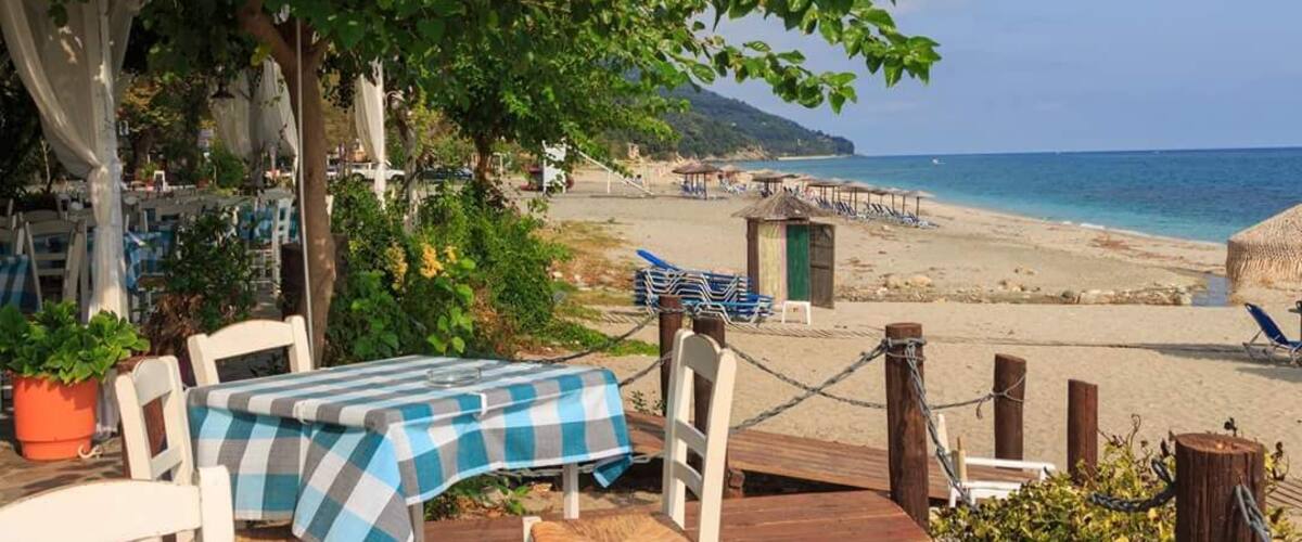 A beachside restaurant with outdoor seating overlooking the sea.