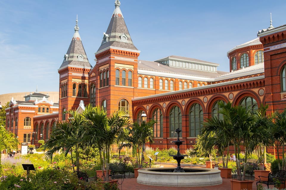 A historic building with two towers and a fountain in the courtyard.