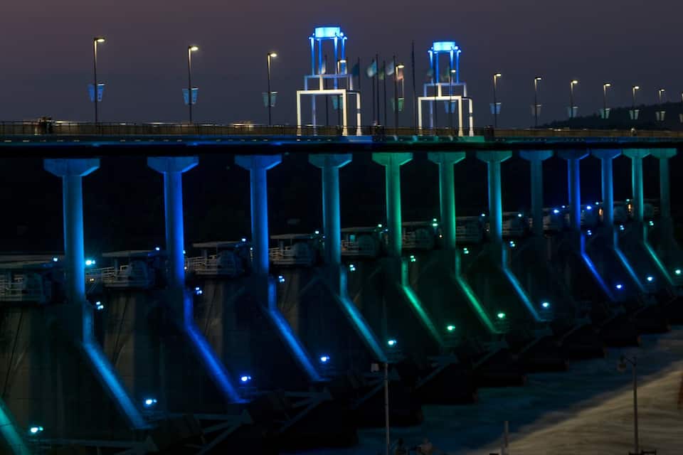 Un pont amb llums blaves il·luminades i una gran estructura al fons.