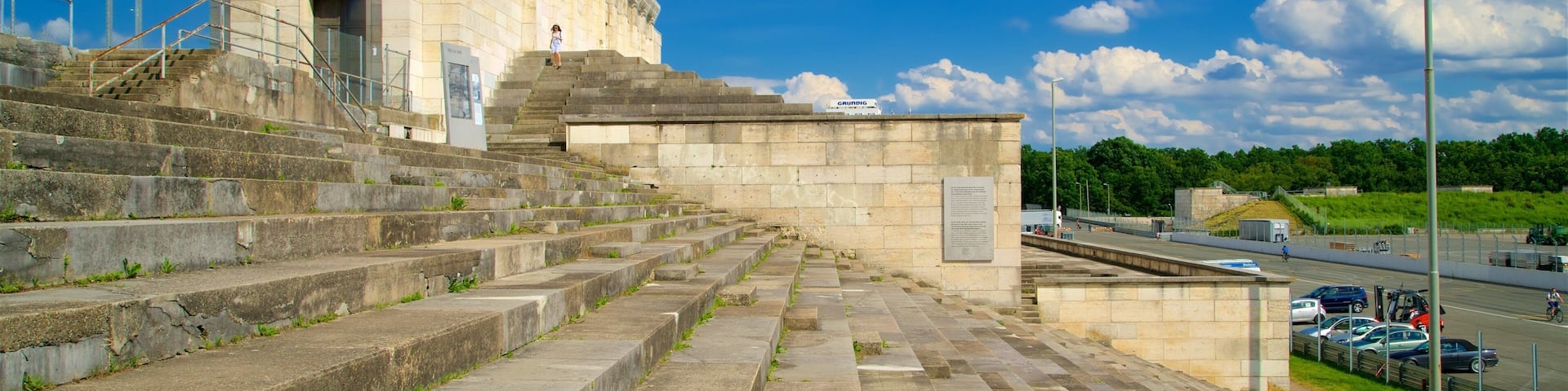 A stone staircase leading up to a large building with a sign reading "Grundig."