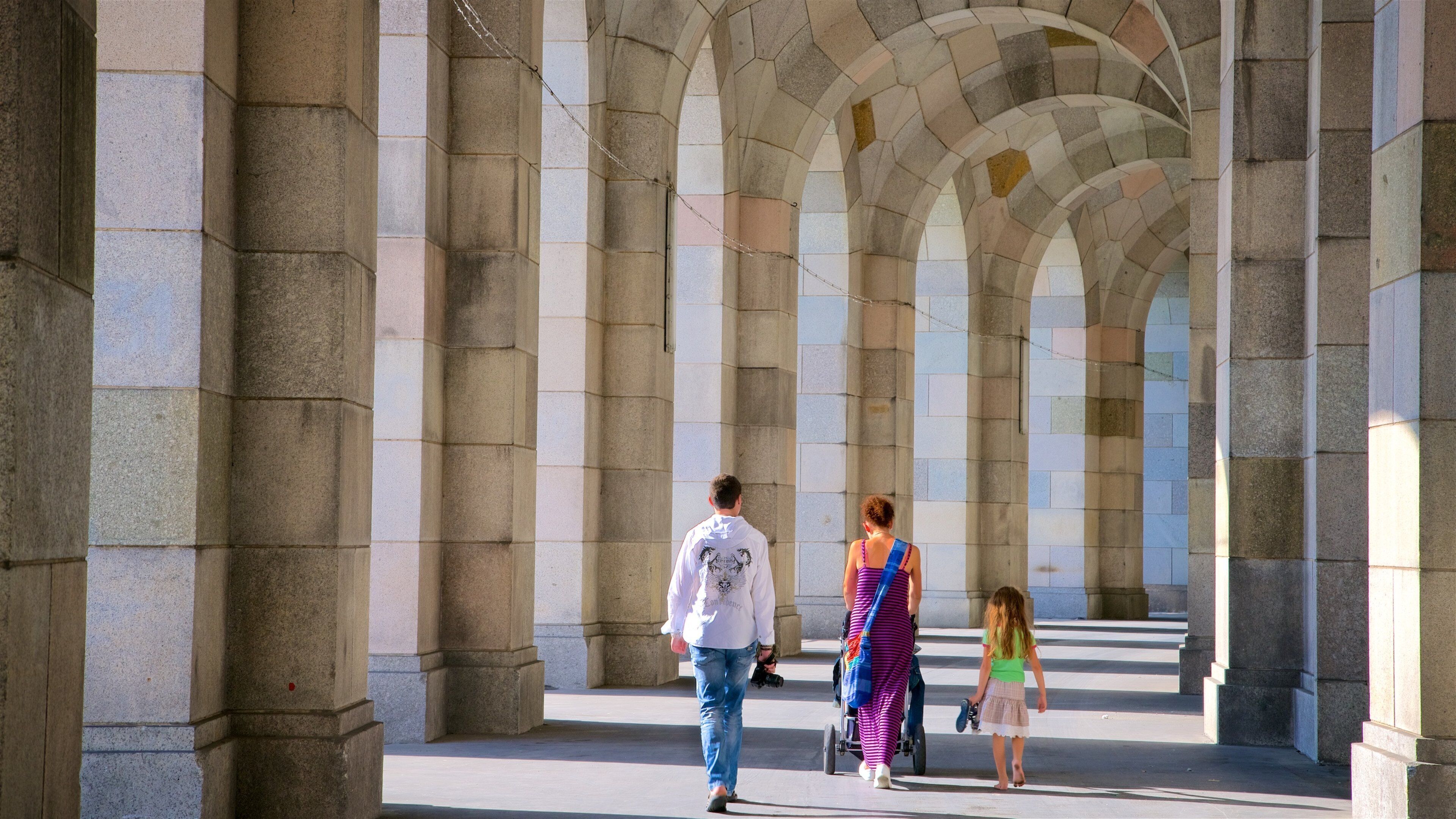 A stone archway corridor with people walking through it.