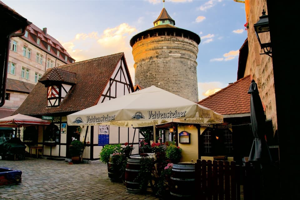 Eine Kopfsteinpflasterstraße mit traditionellen Fachwerkhäusern, einem Turm und einem Bierzeltdach.