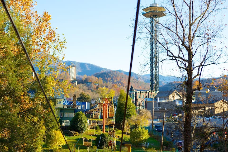 A park with a playground, a tall tower, and buildings in the background.