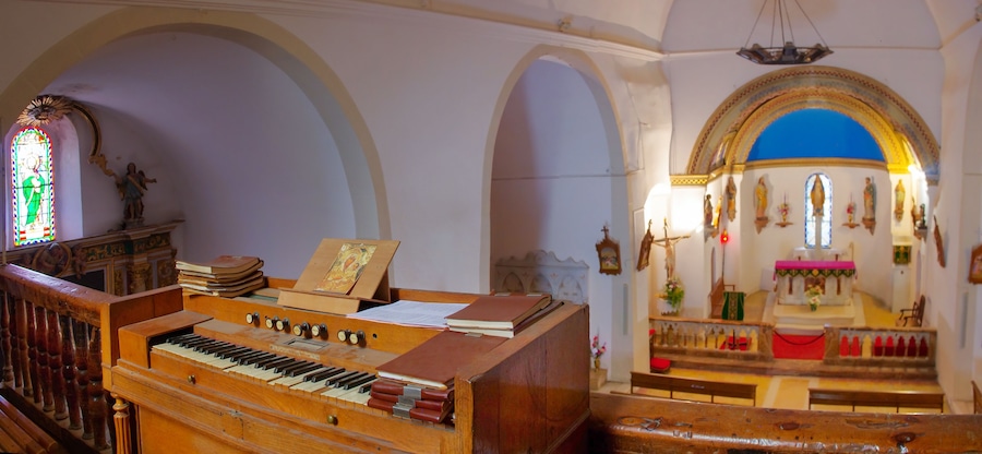 Un órgano con partituras, una vidriera y el interior de una iglesia con techos abovedados y estatuas religiosas.