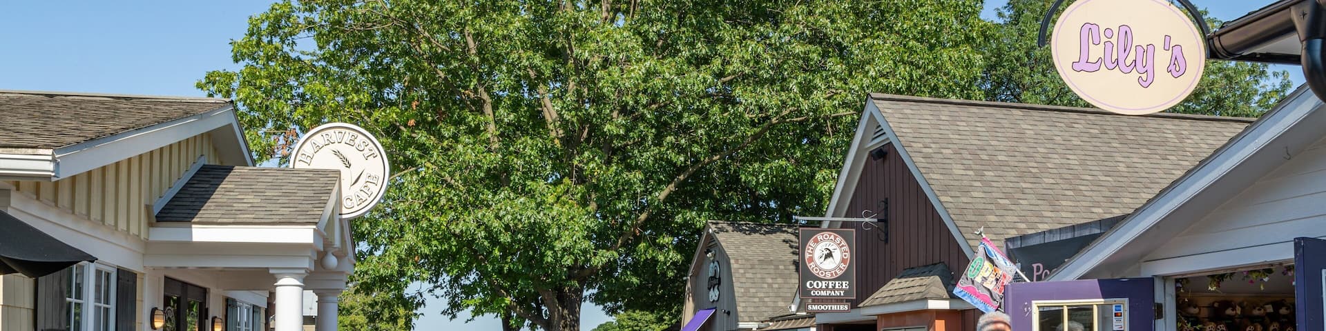 A bustling outdoor shopping area with various shops, including a coffee shop and a store with a purple sign.