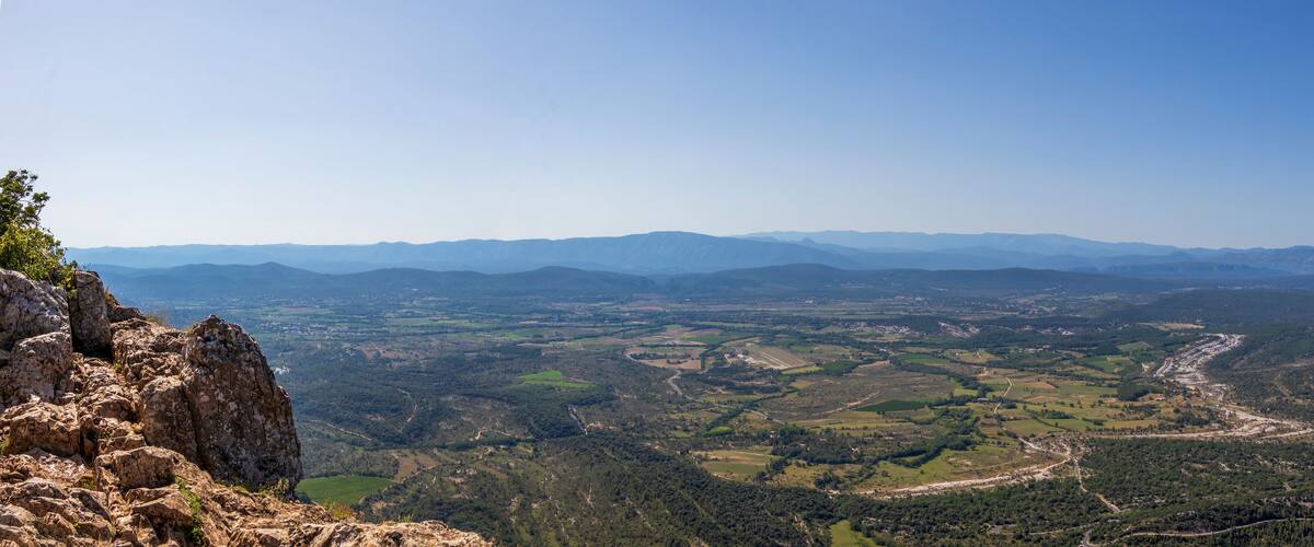 A mountainous landscape with a valley, winding roads, and distant mountains.