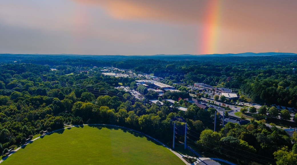 an aerial shot of the vast miles of lush green trees and grass with buildings nestled among the trees and powerful clouds and a rainbow at Etowah River Park in Canton Georgia USA